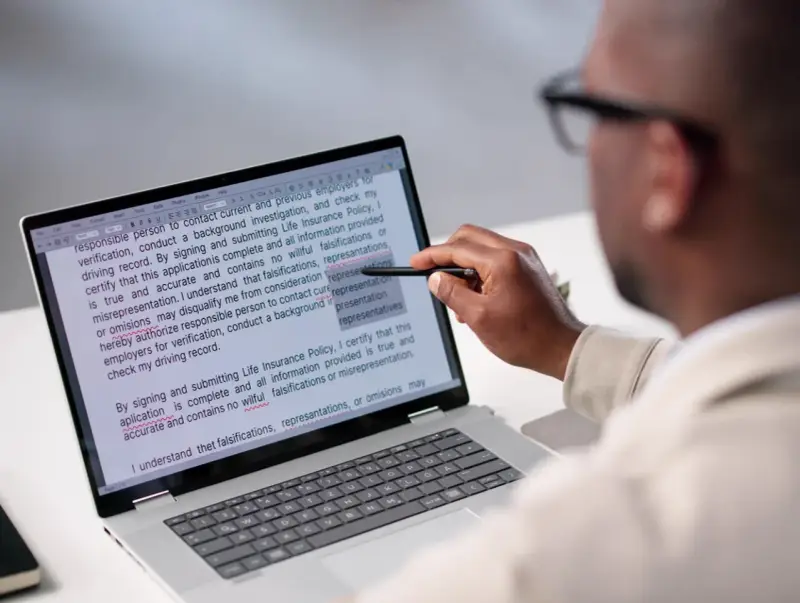 Un homme examine un document sur un écran d'ordinateur, soulignant des passages pour apprendre comment reconnaître une pièce fautée.